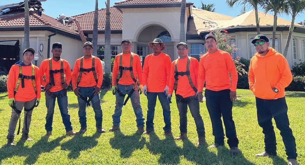 The team of workers in orange attire and safety harnesses.