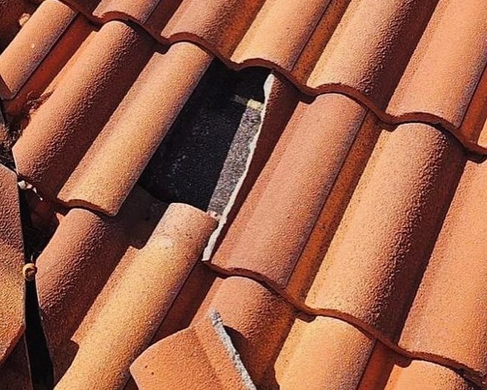A close-up view of damaged red clay roof tiles