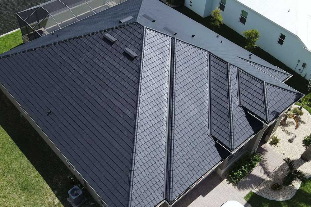 A modern house with a dark gray metal roof featuring multiple sharp angles and ridges