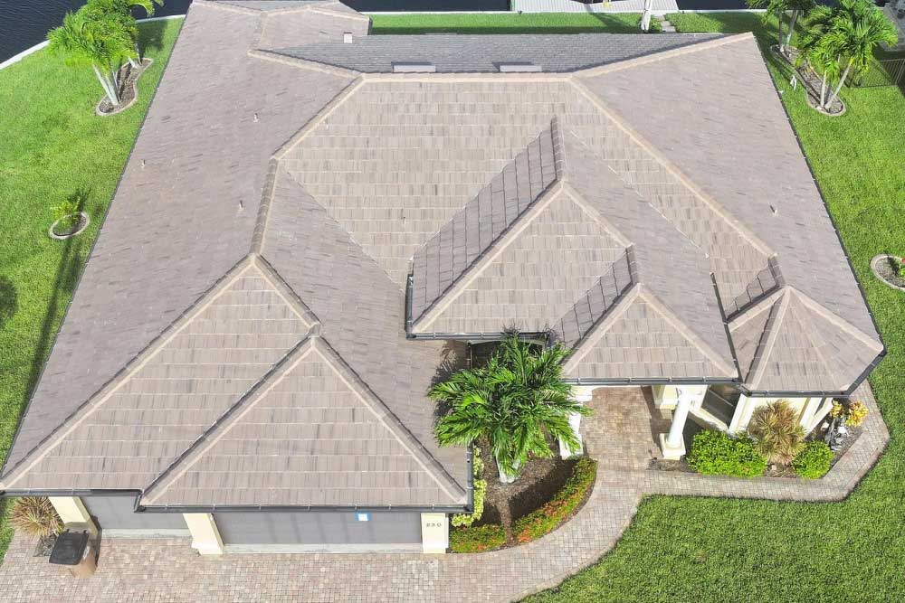 A large house with a complex, multi-angled taupe-colored tile roof