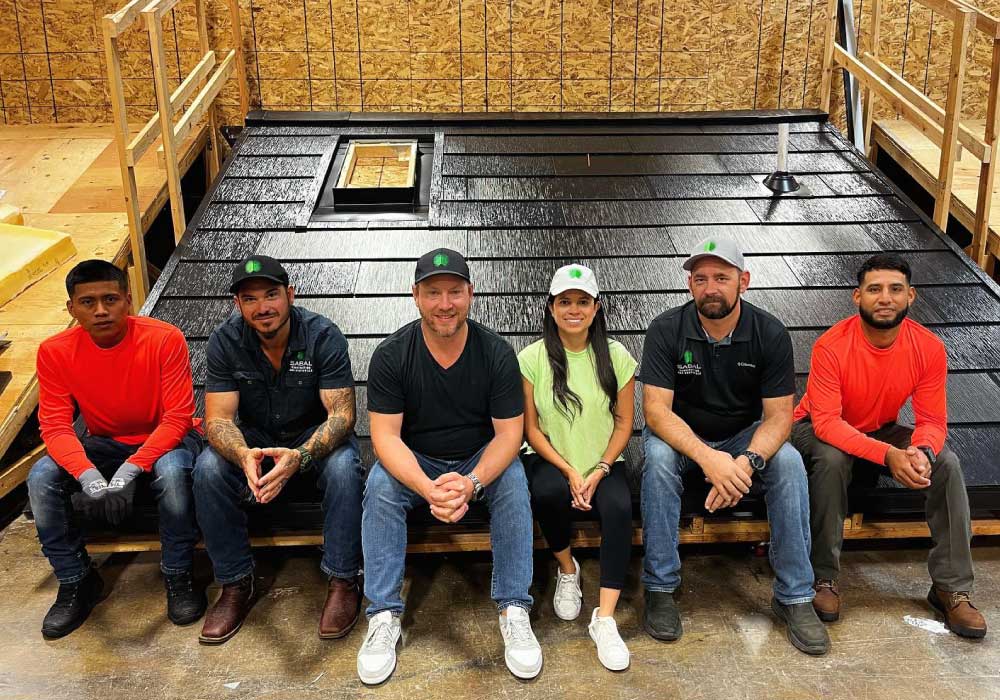 A group of six people sitting in front of a black roof structure.