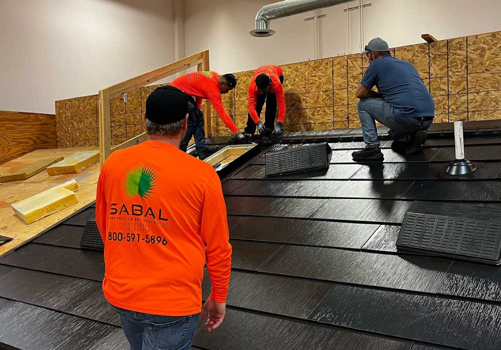 Four workers install materials on a workshop's roof structure