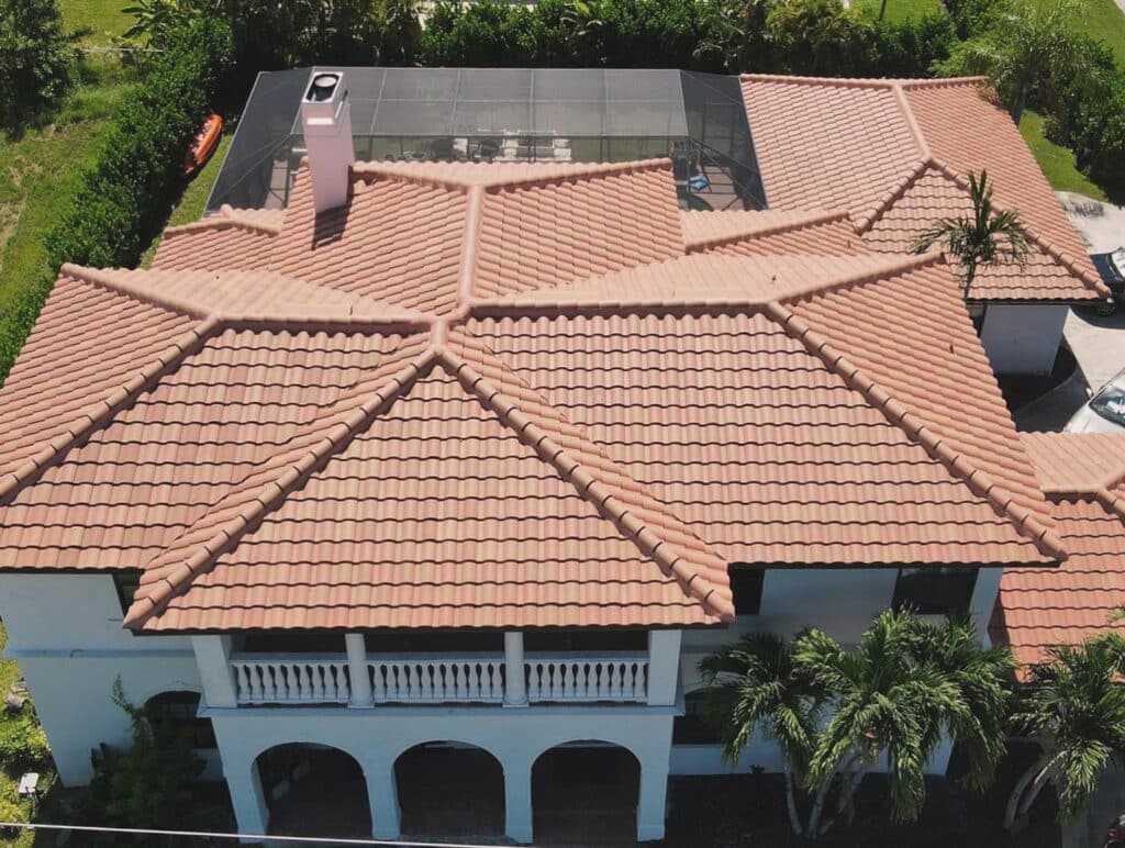Aerial view of a house with a terracotta tile roof and screened pool area.