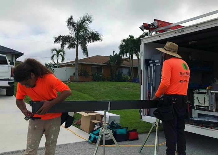 Two workers from Sabal Construction preparing materials near a truck.